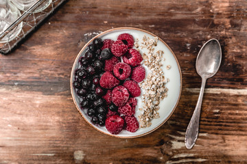 Raspberries and blueberries in a Bowl. Healthy breakfast concept with yoghurt and muesli