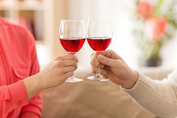 celebration, drinks and alcohol concept - hands of couple clinking red wine glasses
