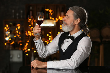 Senior man drinking wine in bar