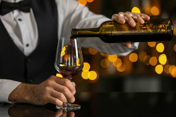 Senior barman pouring wine into glass in pub