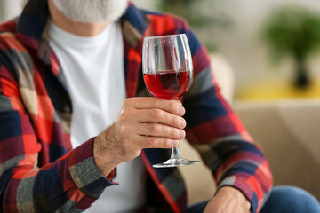Senior man drinking wine at home, closeup