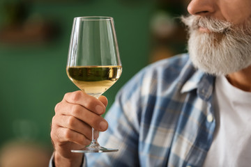 Senior man drinking wine at home, closeup