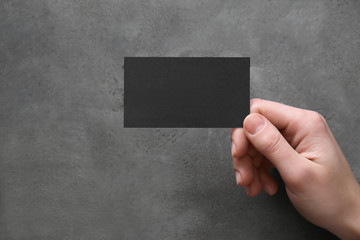 Hand with blank business card on grunge background