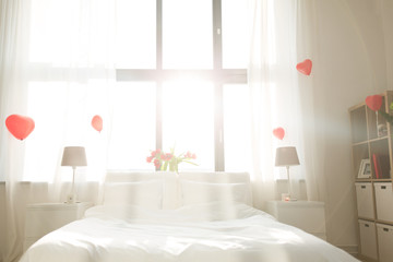 coziness, interior and romantic date concept - cozy bedroom decorated for valentines day