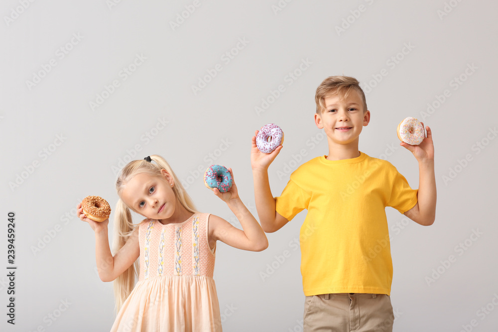 Poster Cute little children with donuts on light background