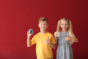 Cute little children with donuts on color background