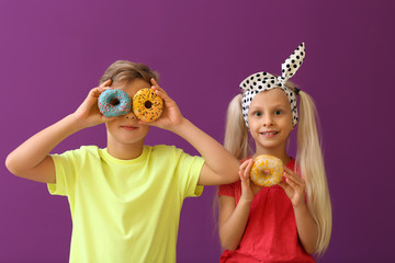Cute little children with donut on color background