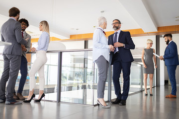 Group of modern business people chatting during coffee break standing in office building