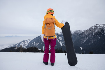 successful snowboarder with snowboard on winter mountain top