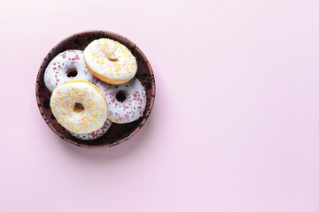 Plate with sweet donuts on color background