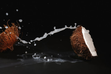 Ripe coconut and splash of milk on dark background