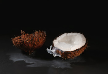Ripe coconut and splash of milk on dark background