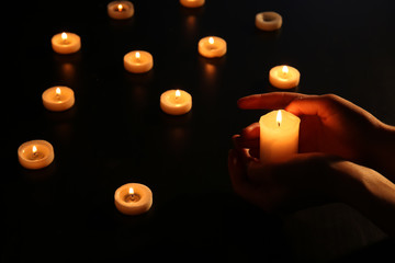 Woman with many burning candles in darkness