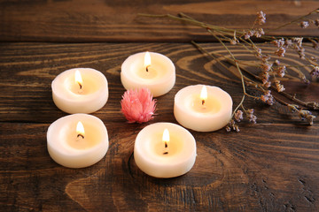 Fototapeta na wymiar Burning candles and flower on wooden table