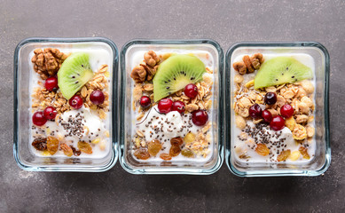 Tasty granola with yogurt in bowls on grey table