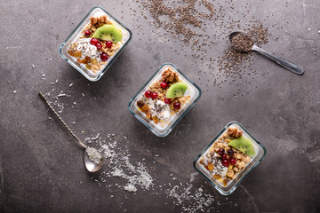 Tasty granola with yogurt in bowls on grey table