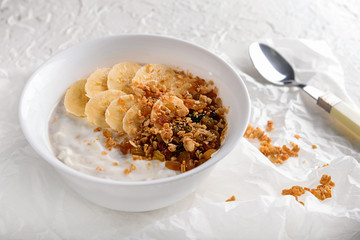 Bowl with tasty granola and yogurt on white table