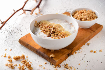 Bowl with tasty granola and yogurt on white table