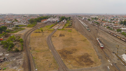 freight train with cisterns and containers on railway station Surabaya Indonesia. Wagons with goods on railroad. Heavy industry. railway station in an asian city among buildings.