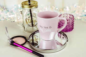 make up set on wooden table with cup of tea top view