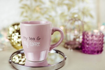 Cup of hot drink with coffee on table with biege and gold decorations.