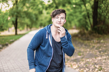 Portrait of young caucasian man with golden round glasses touching his chin, smiling. White...