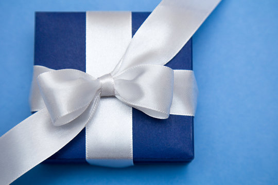 Подарок. Синяя коробочка с белым бантом на голубом фоне
