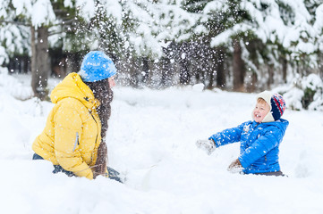 Outdoor portrait Mother and child playing in the winter park. showered with snow
