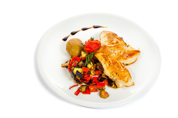 Grilled chicken breast with vegetables on white plate.