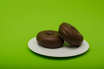 two chocolate donuts on a plate