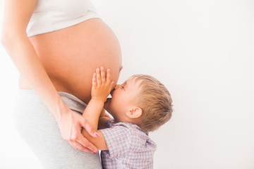 Little boy kiss the pregnant belly of mom