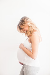 Pregnant woman near the wall looks on the belly