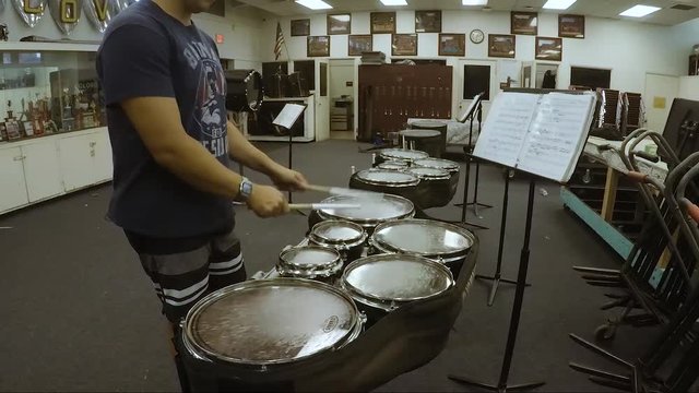 Person drumming and rehearsing in the band room.