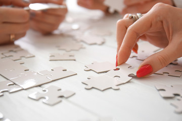 People doing puzzle at table, closeup
