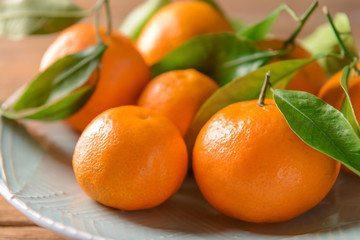 Plate with tasty tangerines on table, closeup