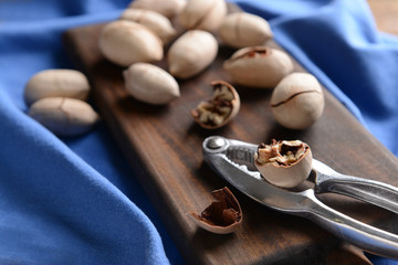 Nutcracker with pecan nuts on wooden board, closeup