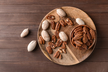 Plate with pecan nuts on wooden background