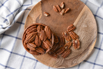 Bowl with pecan nuts on wooden plate