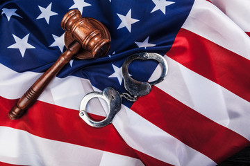 Gavel, handcuffs and american flag on wooden background.