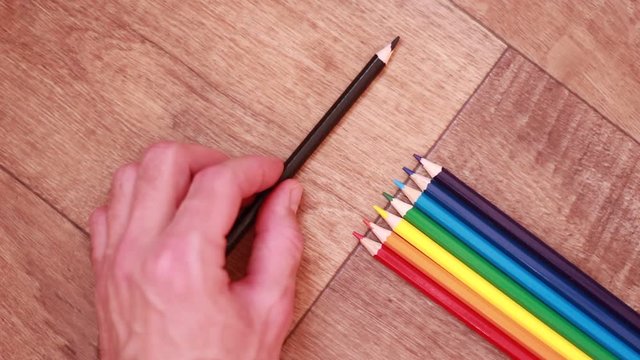 Putting black pencil athwart multicolored pencils