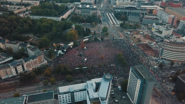 Aerial drone panning above Cheminitz, Germany city as thousands people attend an open air rock concert to stand together against racism with one large stage and people sprawled throughout the streets