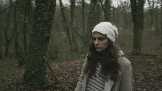 close shot of a girl walking on a grass and mud track in a french forest