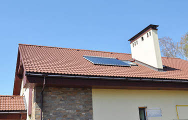 Solar water heater on modern house roof top with skylight, gutter and chimney