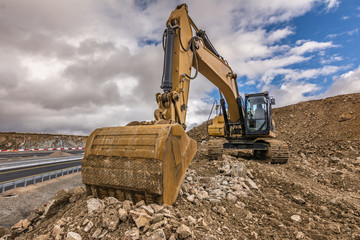 Excavator in the works of extension of a road
