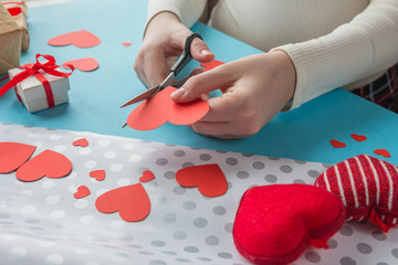 hands of the girl prepare a gift for Valentine's Day, handmade Valentines on a blue background