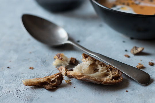 Bits of bread and spoon near pumpkin cream soup