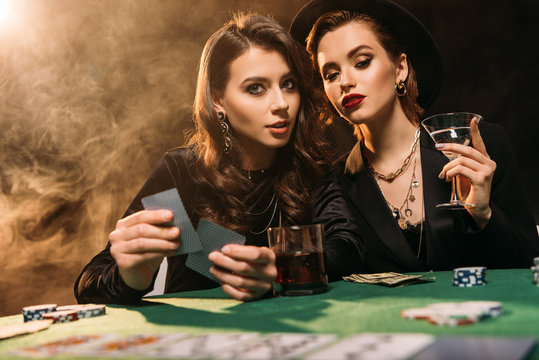 attractive girls playing poker at table in casino