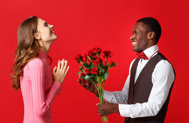 valentine's day concept. happy young couple with heart, flowers, gift on red