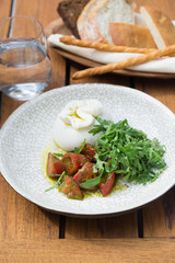 Buratta cheese served with red tomatoes and rocket salad for lunch on terrace of restaurant