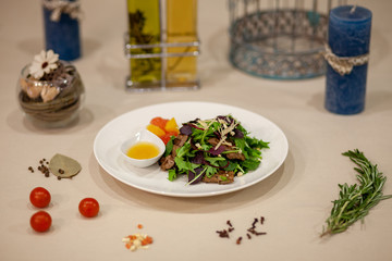 Meat, fish, salads on the table in white plate in the interior with olive oil